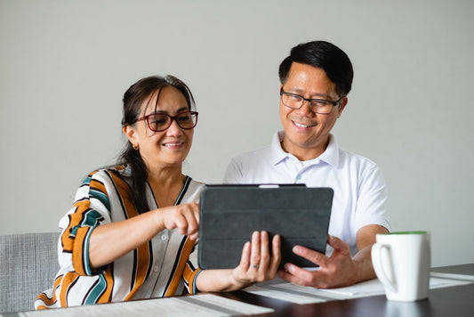 Happy couple using a tablet together at home, promoting mental health and wellness community.